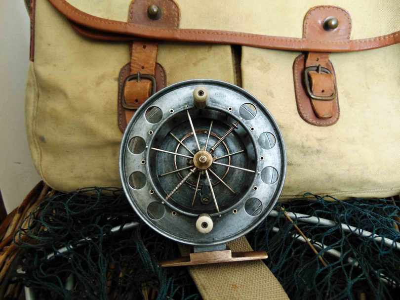 Picture of an Allcocks Aerial fishing reel cleaned sitting in front of a Brady fishing bag
